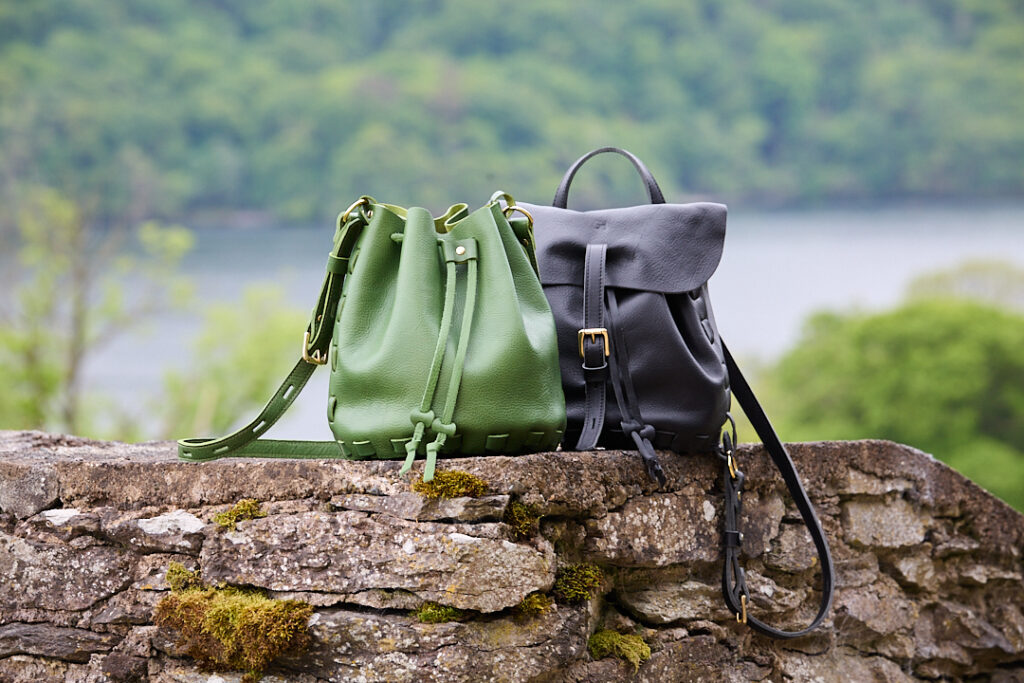 Parnassus black and green leather bags sit on a wall with Ullswater and the Lake District fells in the background
